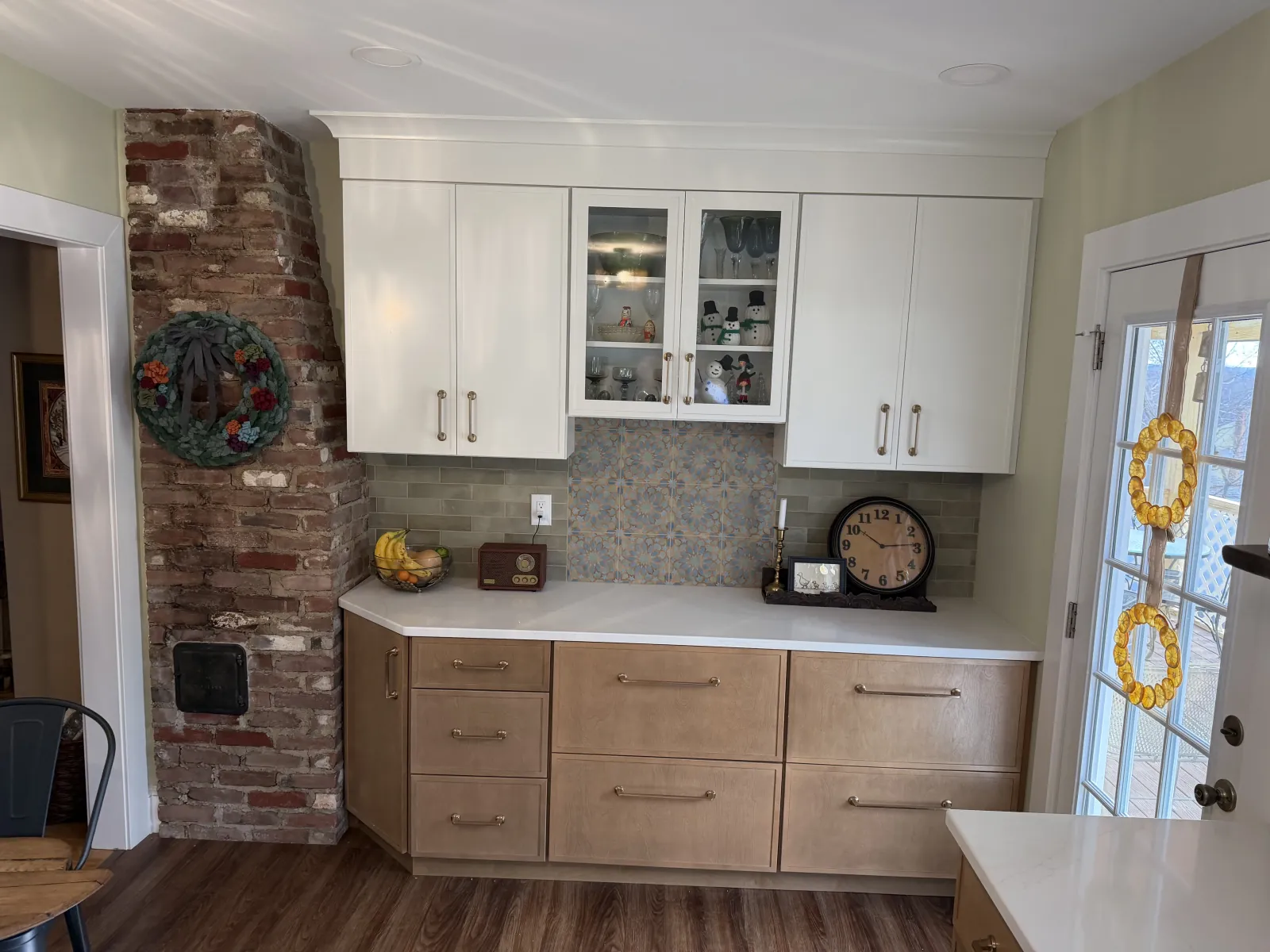 Two-tone kitchen with white uppers and wood base by exposed brick